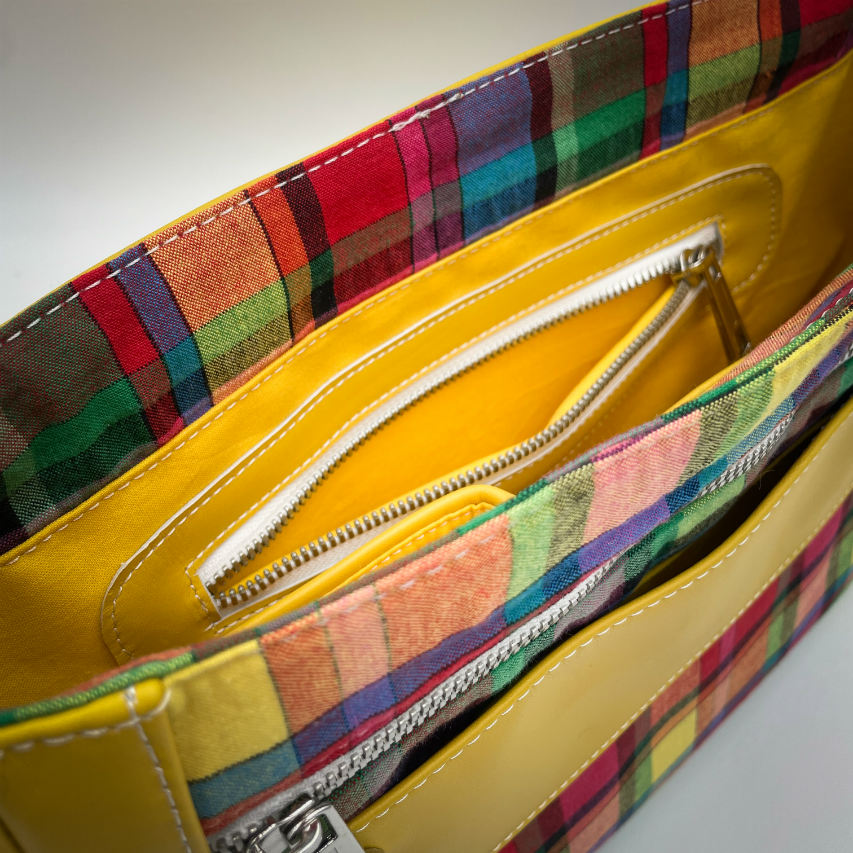 A satchel made of blood-red faux leather and multicolored madras fabric.