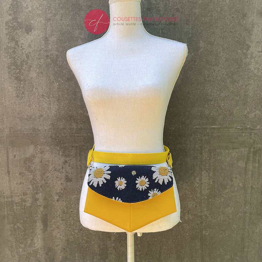 A small bag made from yellow faux leather and a fabric coupon with white and yellow daisies on a navy blue background.