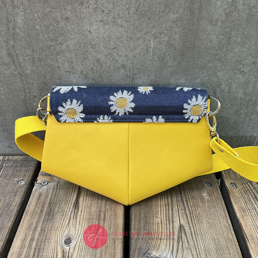 A small bag made from yellow faux leather and a fabric coupon with white and yellow daisies on a navy blue background.