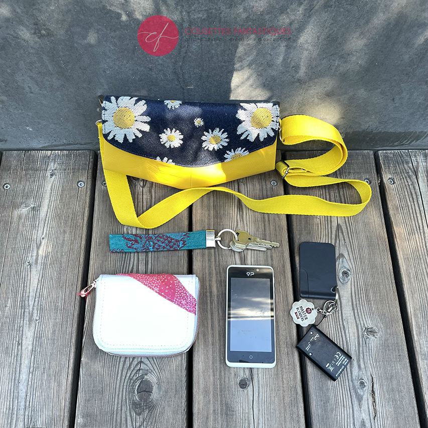 A small bag made from yellow faux leather and a fabric coupon with white and yellow daisies on a navy blue background.