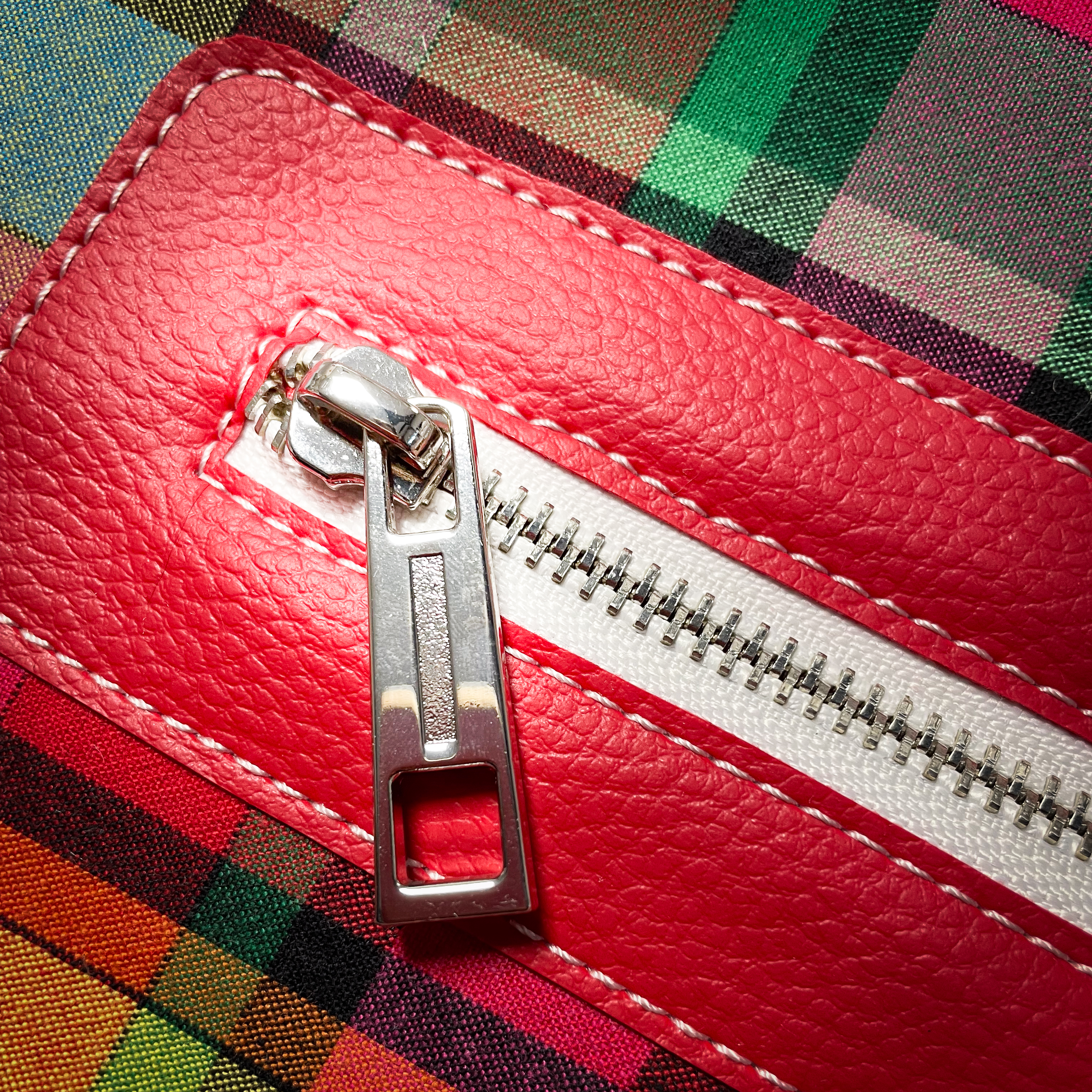 A shoulder bag made of blood-red faux leather and multicolored madras fabric.