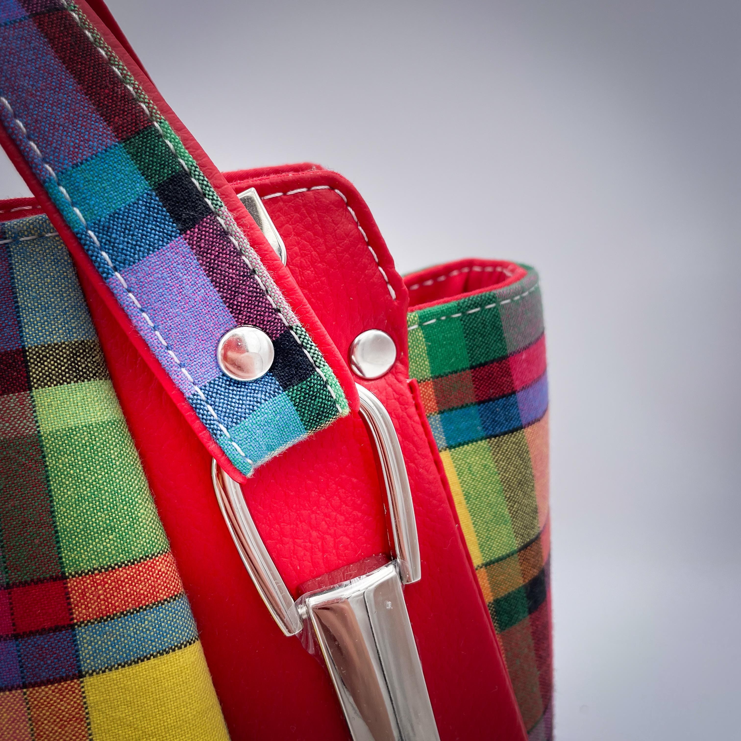 A shoulder bag made of blood-red faux leather and multicolored madras fabric.