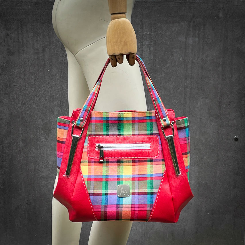 A shoulder bag made of blood-red faux leather and multicolored madras fabric.