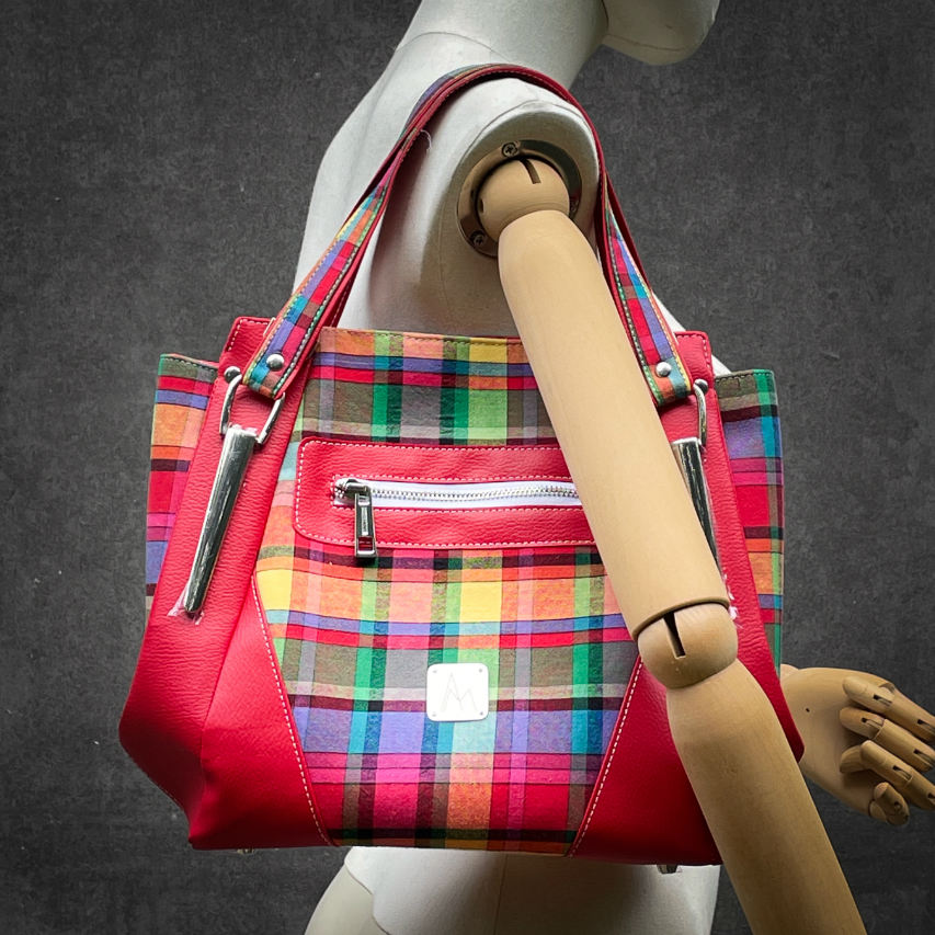 A shoulder bag made of blood-red faux leather and multicolored madras fabric.