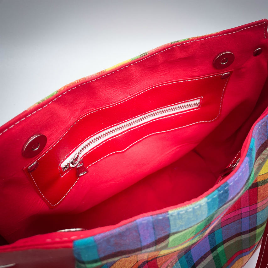 A shoulder bag made of blood-red faux leather and multicolored madras fabric.