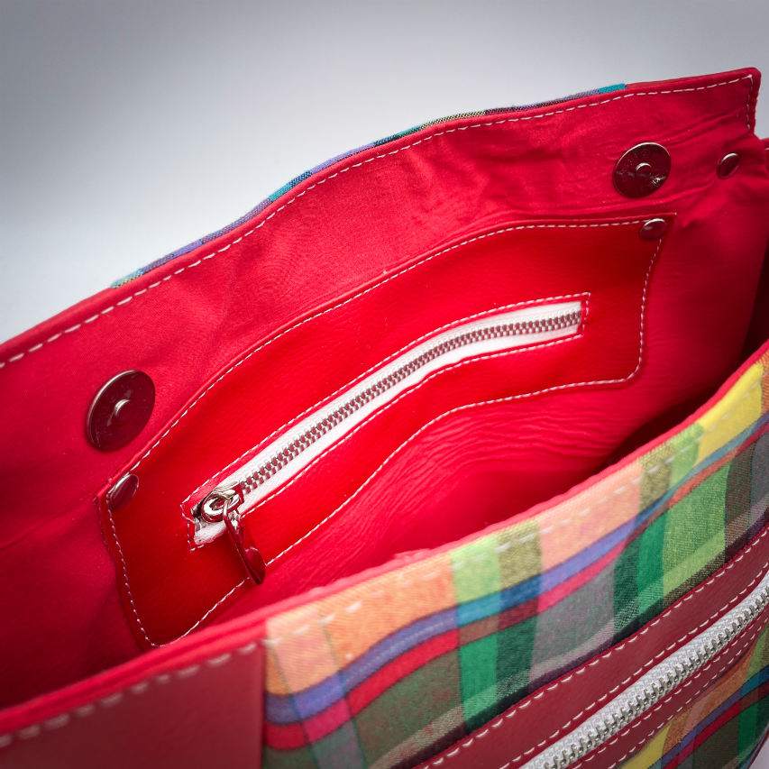 A shoulder bag made of blood-red faux leather and multicolored madras fabric.