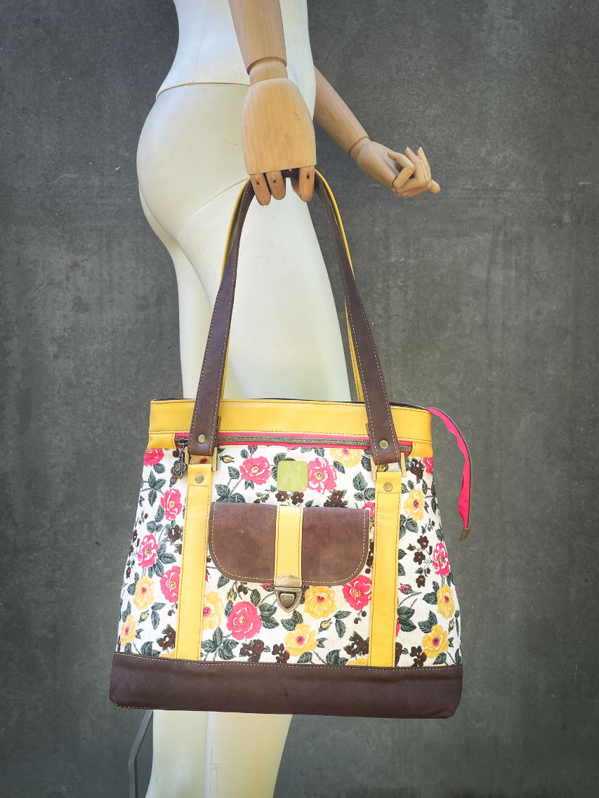 A shoulder bag made from chocolate and yellow leathers combined with a floral canvas featuring pink and yellow flowers.