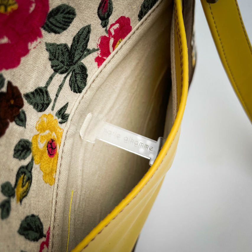 A shoulder bag made from chocolate and yellow leathers combined with a floral canvas featuring pink and yellow flowers.