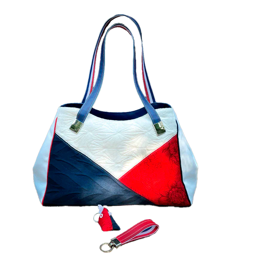 A shoulder bag made with several babywearing wrap coupons (blue, white, and red) and white and blue faux leather.