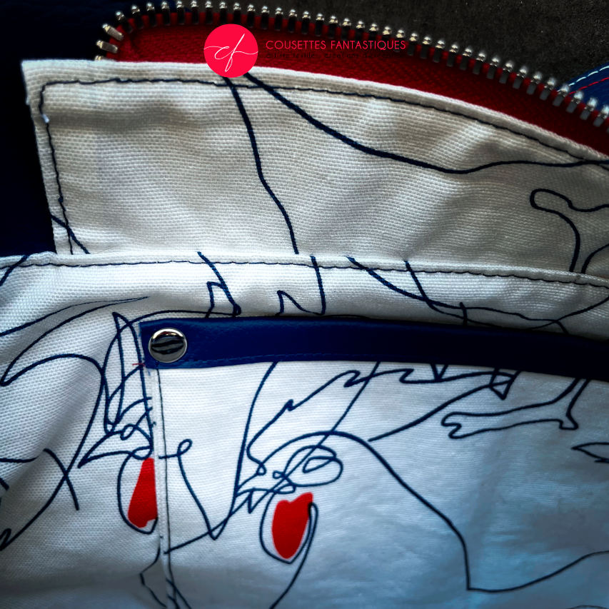 A shoulder bag made with several babywearing wrap coupons (blue, white, and red) and white and blue faux leather.