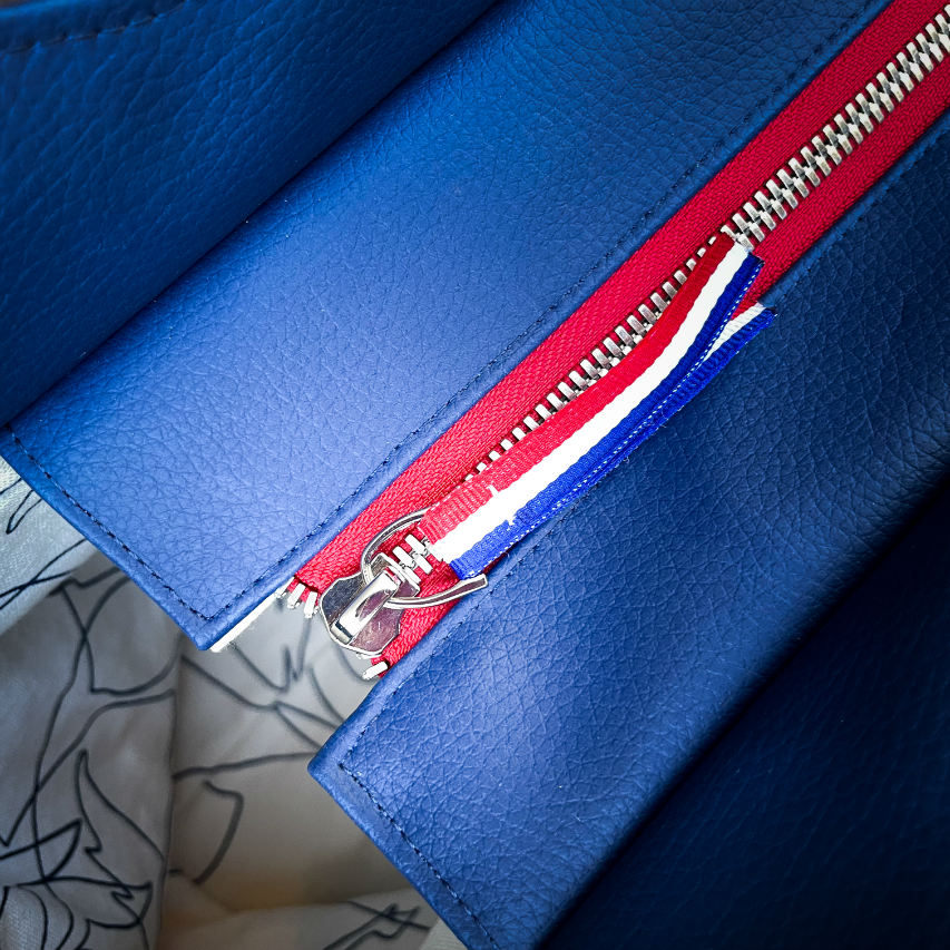 A shoulder bag made with several babywearing wrap coupons (blue, white, and red) and white and blue faux leather.