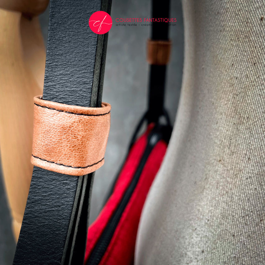 A shoulder bag made of black and caramel leathers, red and black velvet upholstery fabric, and red and black satins.