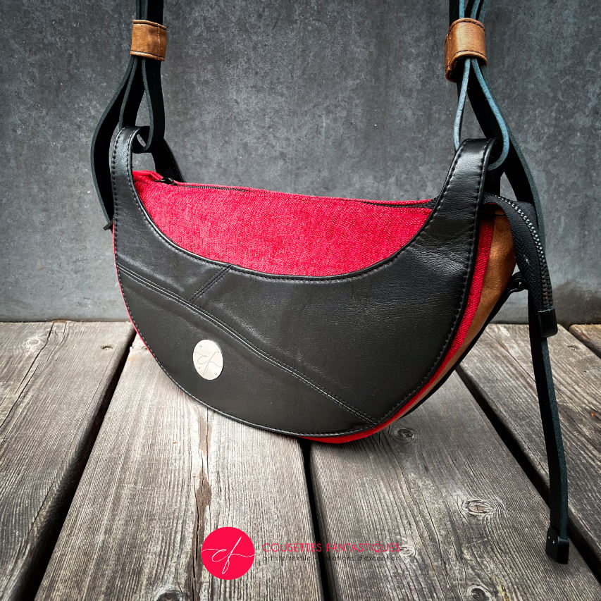 A shoulder bag made of black and caramel leathers, red and black velvet upholstery fabric, and red and black satins.