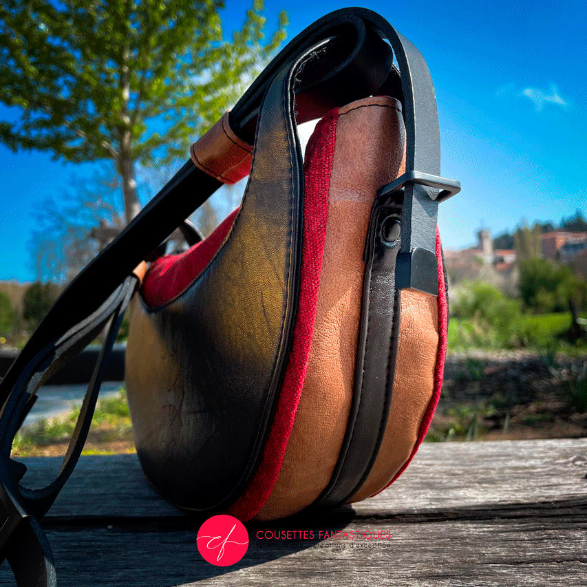 A shoulder bag made of black and caramel leathers, red and black velvet upholstery fabric, and red and black satins.