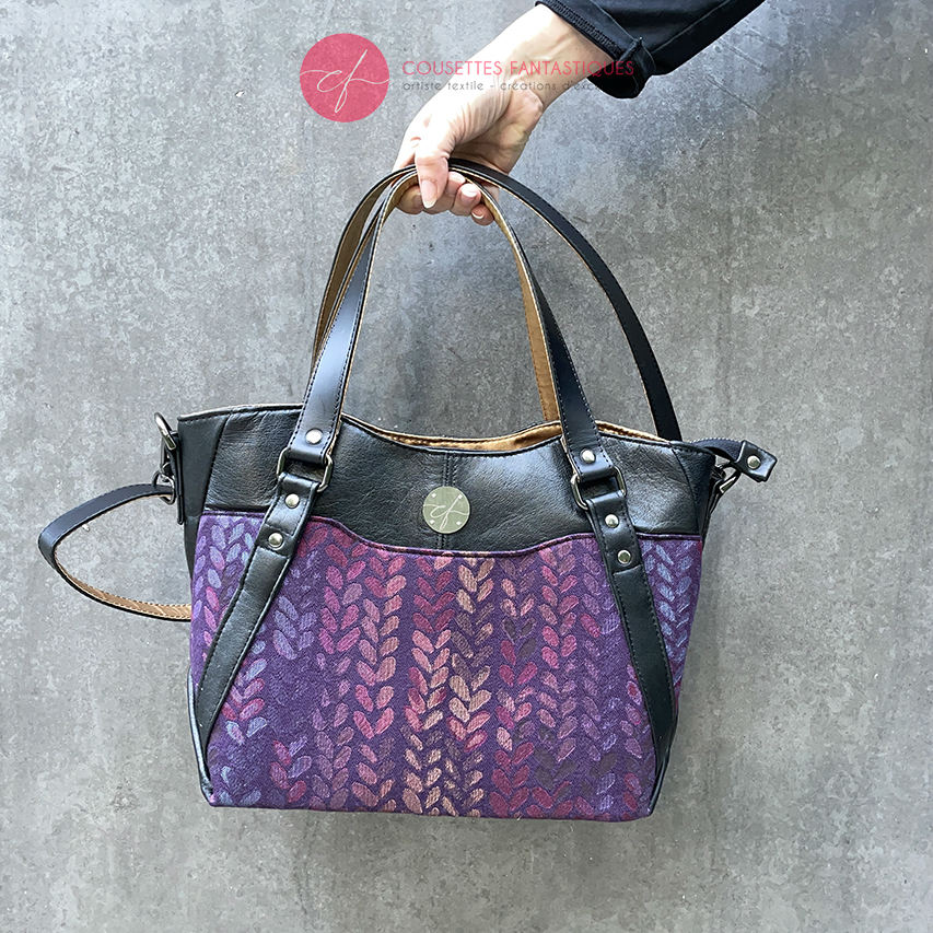 A shoulder bag made from fabric in purples, purples, pinks... with droplet motifs, and upcycled black lamb leather.