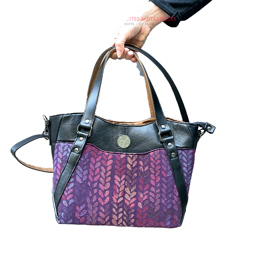 A shoulder bag made from fabric in purples, purples, pinks... with droplet motifs, and upcycled black lamb leather.