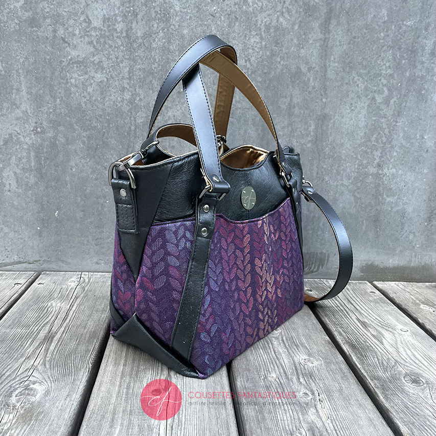 A shoulder bag made from fabric in purples, purples, pinks... with droplet motifs, and upcycled black lamb leather.