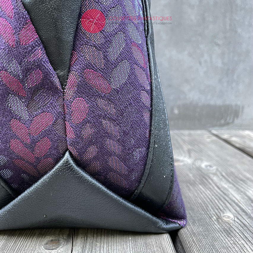 A shoulder bag made from fabric in purples, purples, pinks... with droplet motifs, and upcycled black lamb leather.