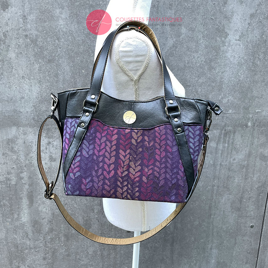 A shoulder bag made from fabric in purples, purples, pinks... with droplet motifs, and upcycled black lamb leather.