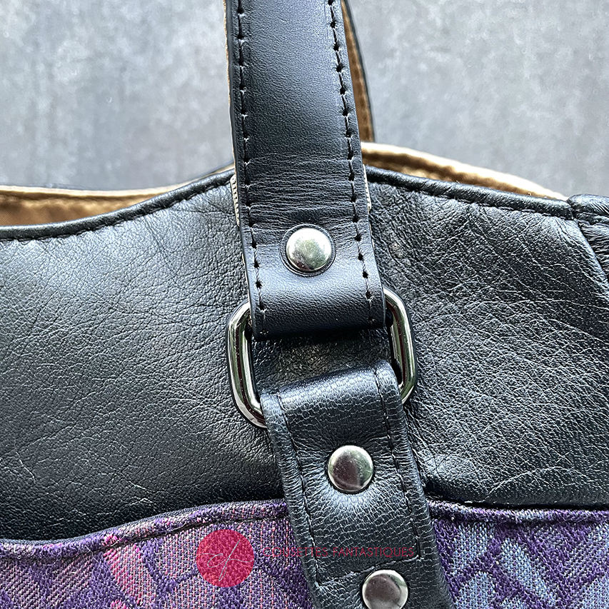 A shoulder bag made from fabric in purples, purples, pinks... with droplet motifs, and upcycled black lamb leather.