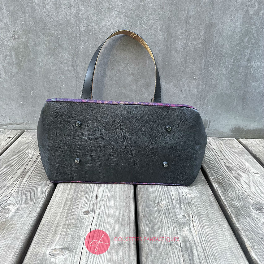 A shoulder bag made from fabric in purples, purples, pinks... with droplet motifs, and upcycled black lamb leather.