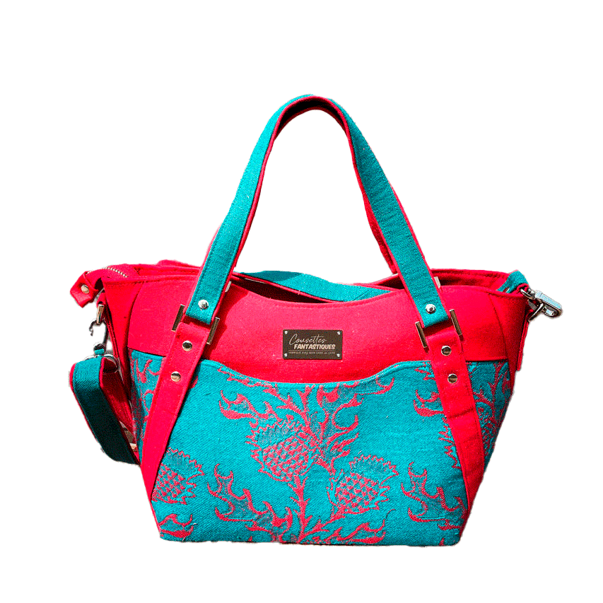 A shoulder bag made from blood red and emerald green babywearing wrap with a thistle pattern, red gabardine, emerald green linen, and synthetic material.