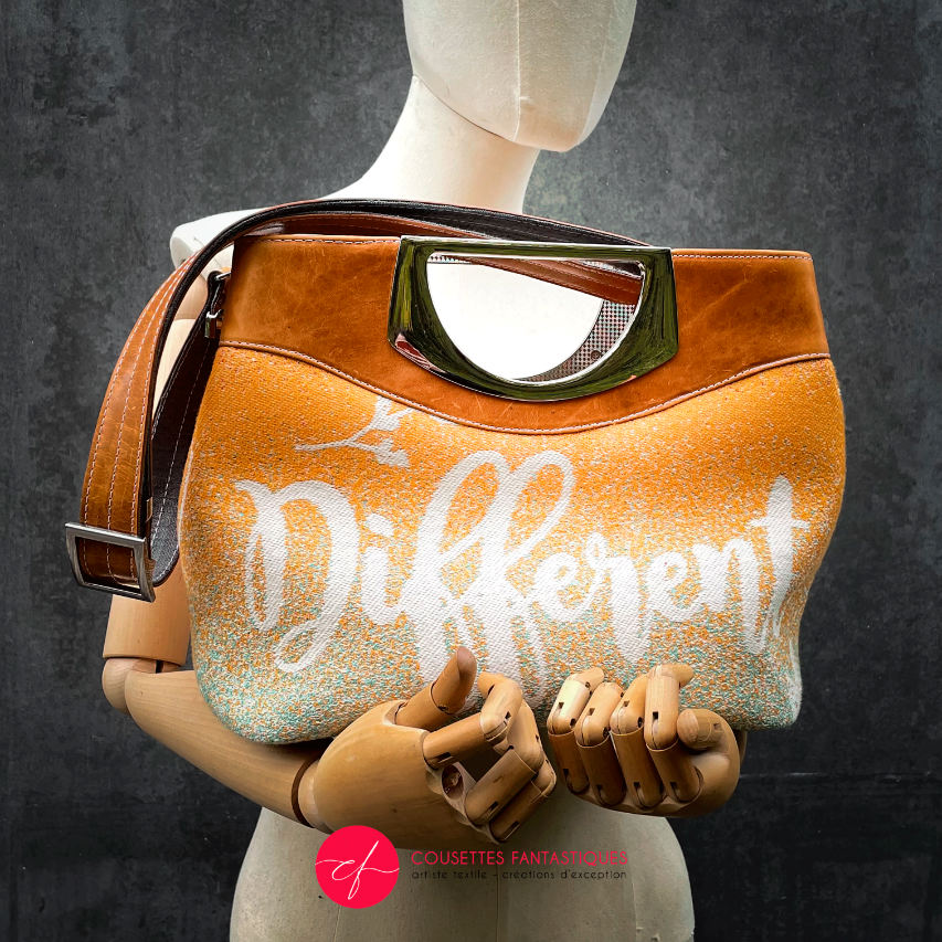 A shoulder bag made of caramel cowhide leather and a gradient-colored babywearing wrap with motivational texts and icons in white.