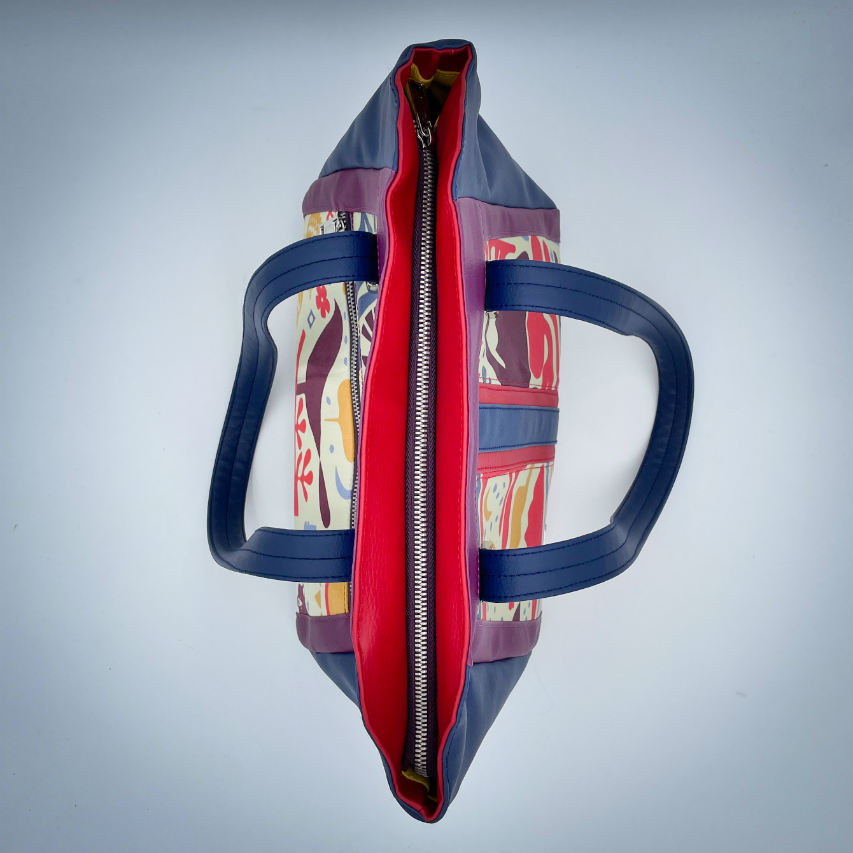 A shoulder bag made from a silk scarf with Scandinavian folklore patterns, combined with red, blue, and purple faux leathers.