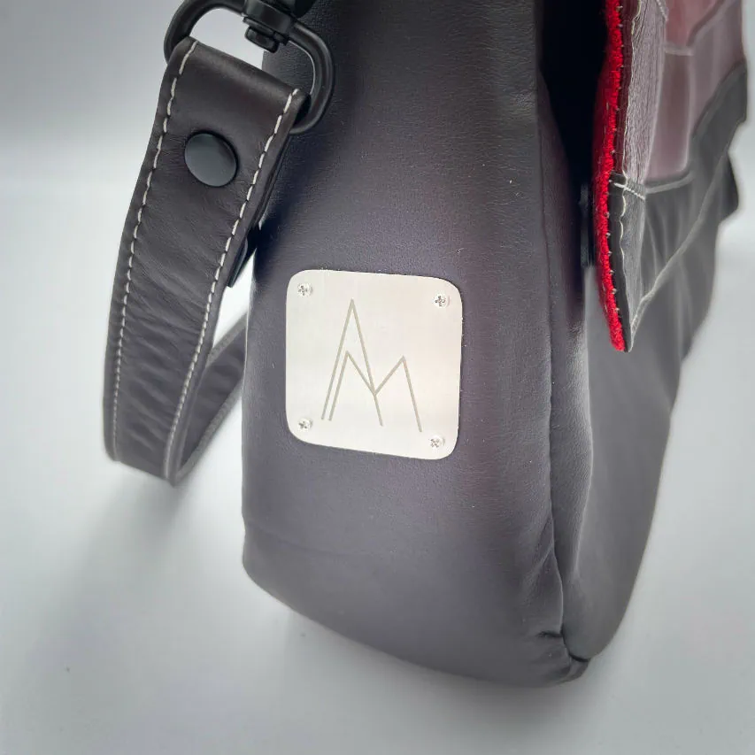 A shoulder bag made of leathers in different shades of red, with brown accents and a red lining.