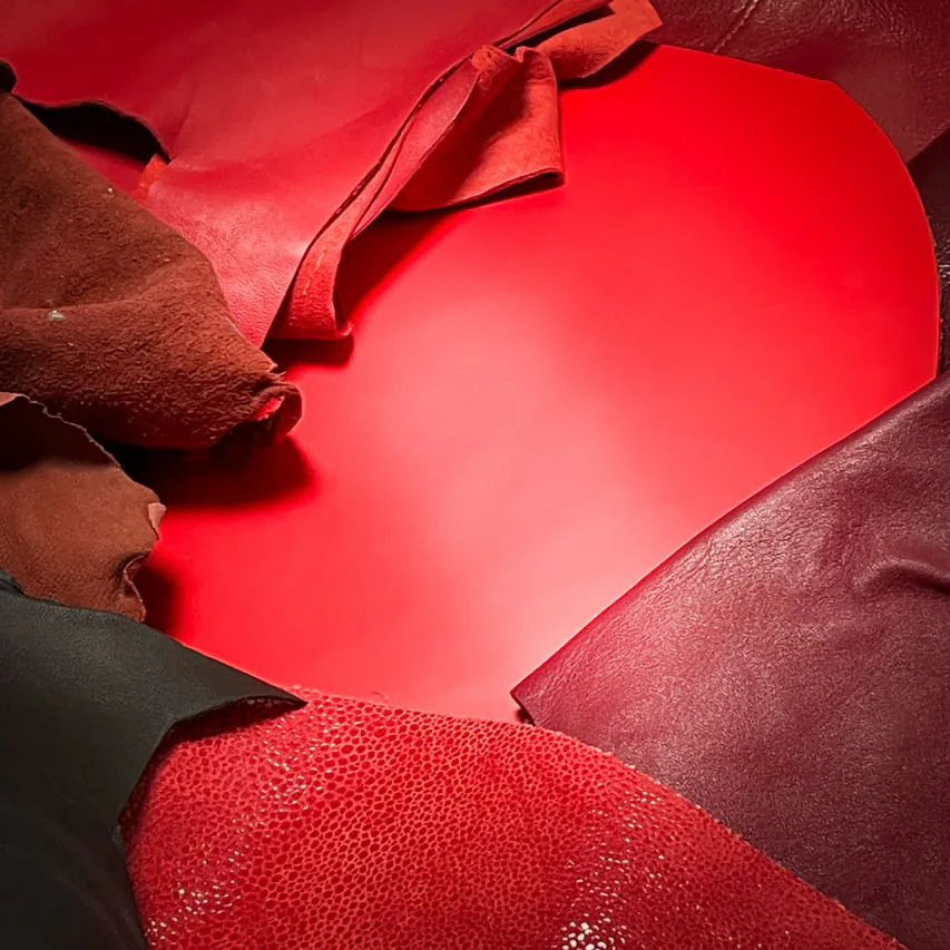 A shoulder bag made of leathers in different shades of red, with brown accents and a red lining.