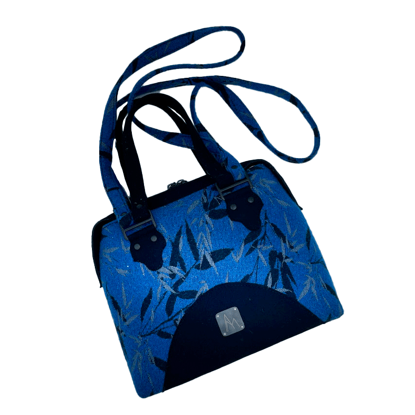 A shoulder bag made from baby wrap fabric featuring a black and royal blue bamboo pattern, paired with boiled black wool and glittered textured leather, complemented by a blue-gray satin lining.