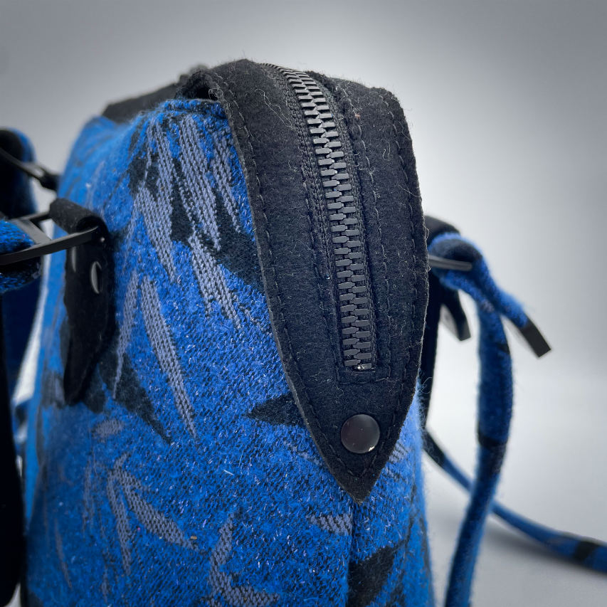 A shoulder bag made from baby wrap fabric featuring a black and royal blue bamboo pattern, paired with boiled black wool and glittered textured leather, complemented by a blue-gray satin lining.