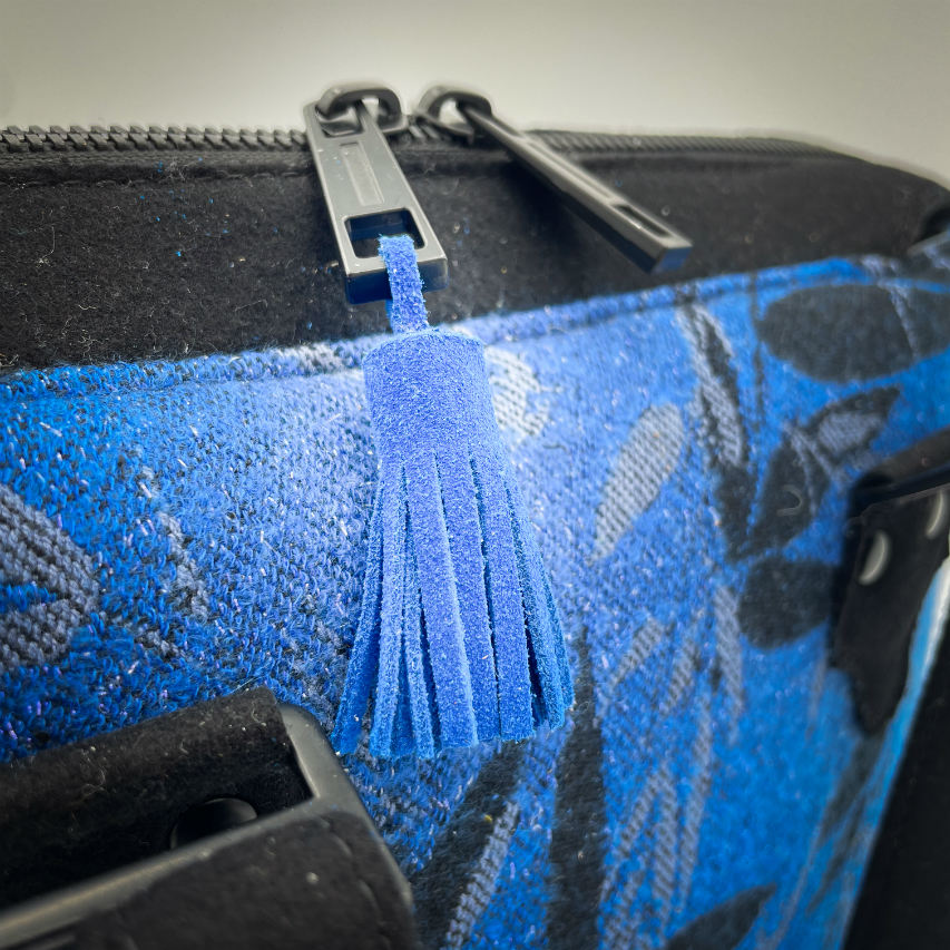 A shoulder bag made from baby wrap fabric featuring a black and royal blue bamboo pattern, paired with boiled black wool and glittered textured leather, complemented by a blue-gray satin lining.