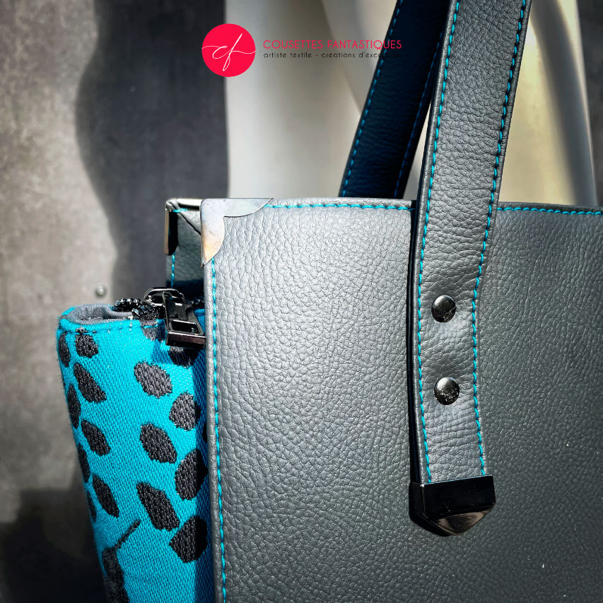 A shoulder bag made of turquoise babywearing fabric with hummingbird and petal motifs, combined with gray and turquoise imitation leather.