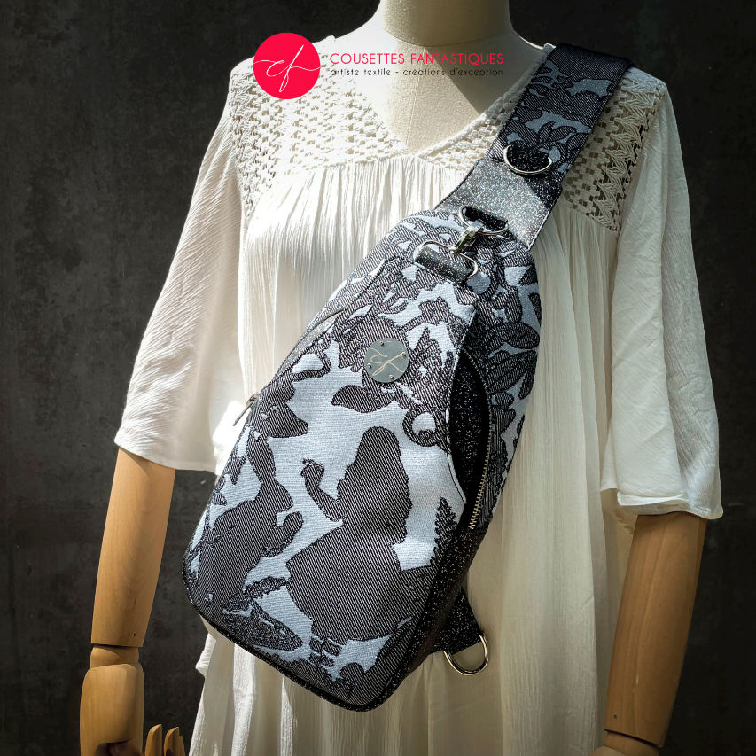 A backpack made from multicolored glitter canvas and a gray-blue, black, and silver-glitter woven wrap with a motif inspired by the Alice in Wonderland story.