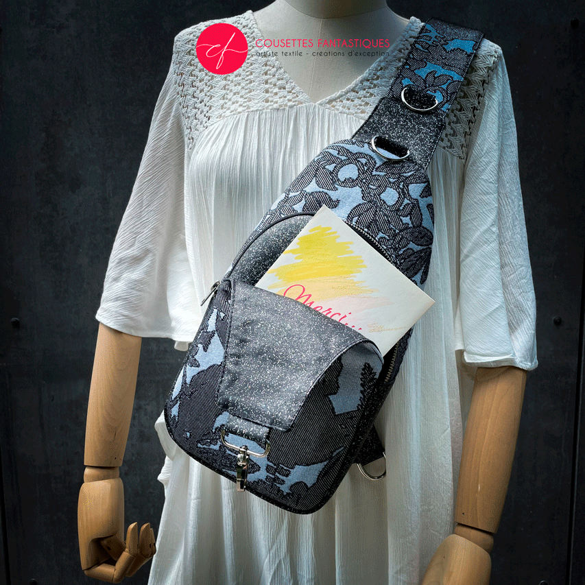A backpack made from multicolored glitter canvas and a gray-blue, black, and silver-glitter woven wrap with a motif inspired by the Alice in Wonderland story.
