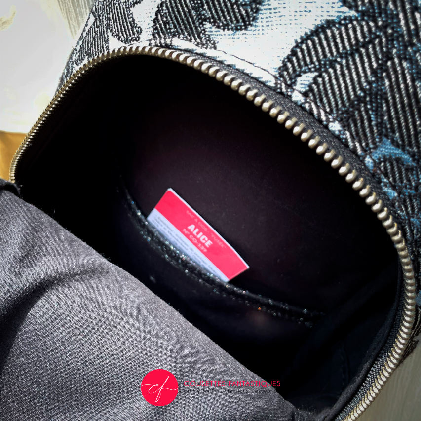 A backpack made from multicolored glitter canvas and a gray-blue, black, and silver-glitter woven wrap with a motif inspired by the Alice in Wonderland story.