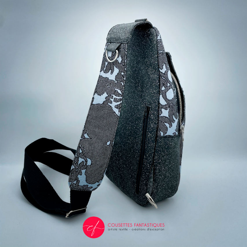 A backpack made from multicolored glitter canvas and a gray-blue, black, and silver-glitter woven wrap with a motif inspired by the Alice in Wonderland story.