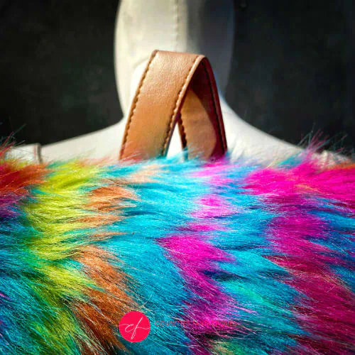 A backpack made from white faux leather and rainbow faux fur.