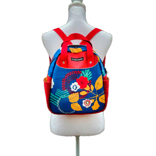 A backpack made from royal blue fabric with yellow, white, and red floral patterns and red embossed fabric on the outside, red and yellow plain linings on the inside.
