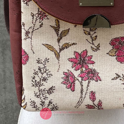 A backpack made with scarf fabric in floral patterns in pink tones on ecru background and brick cork.