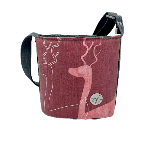 A small “bucket” bag made with delicate pink canvas featuring two white deer silhouettes and gray high-fashion denim.