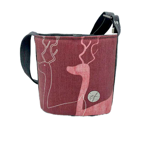 A small “bucket” bag made with delicate pink canvas featuring two white deer silhouettes and gray high-fashion denim.