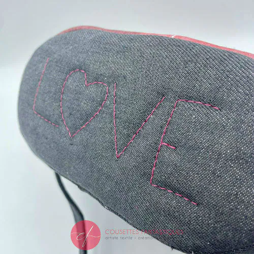 A small “bucket” bag made with delicate pink canvas featuring two white deer silhouettes and gray high-fashion denim.