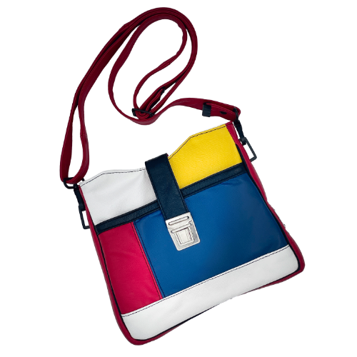 A crossbody bag made of different leathers in royal blue, deep red, bright yellow, white, and black.