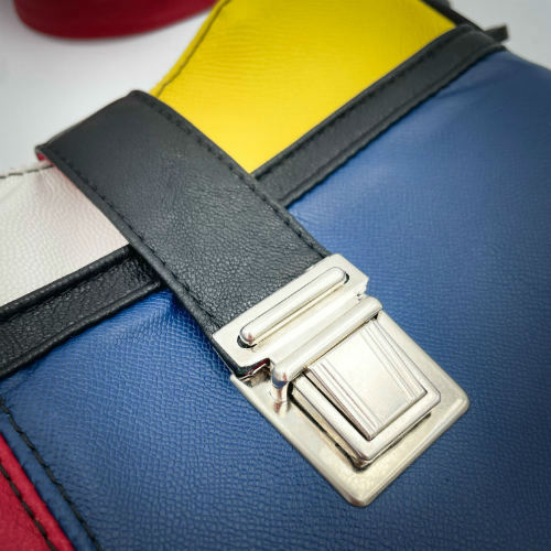 A crossbody bag made of different leathers in royal blue, deep red, bright yellow, white, and black.