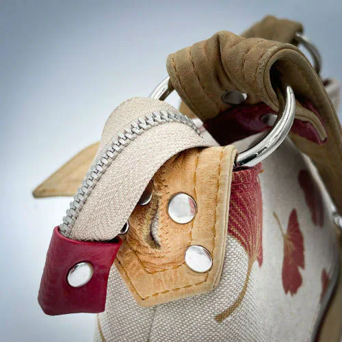 A rectangular crossbody bag made from camel colored leather and a red Ginkgo Biloba leaves patterned polycotton canvas.