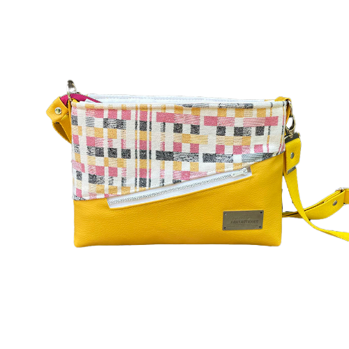 A rectangular messenger bag made from black, white, pink, and yellow babywearing wrap fabric with a geometric pattern, and sunflower yellow faux leather.