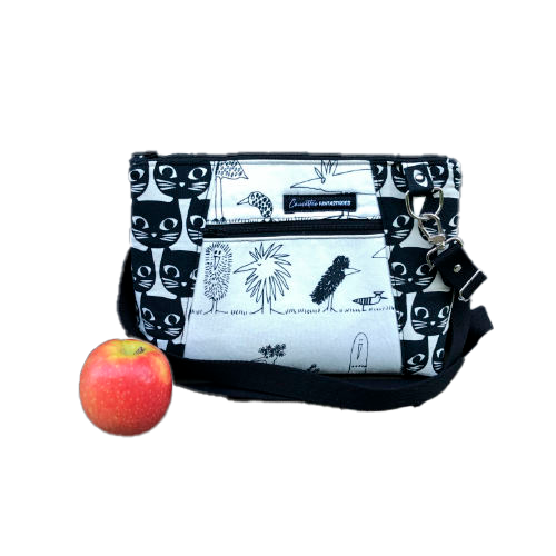 A trapezoid messenger bag made from black and white cotton fabrics on the outside with stylized cat and bird motifs, matched with bird-themed cotton cretonne on the inside.