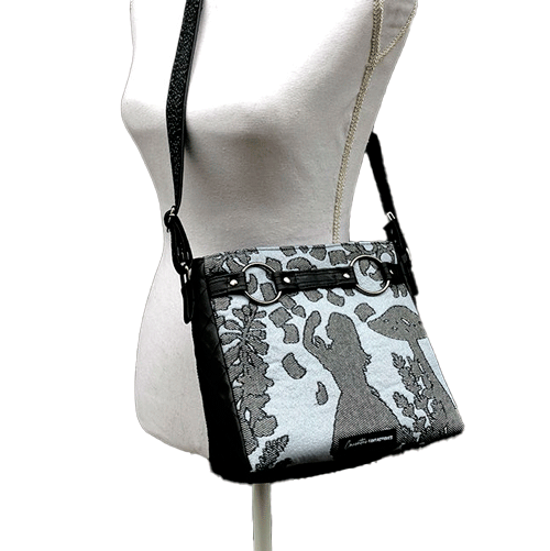 A trapezoid crossbody bag made from a black, gray-blue, and silver “Alice in Wonderland” babywearing scarf, paired with hand-quilted black faux leather.